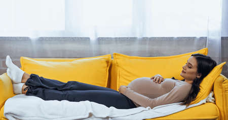 Pregnant woman relaxing on sofa at homeの写真素材