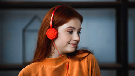 Red haired teenager in headphones at homeの写真素材