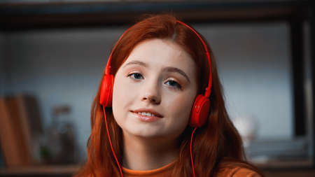Smiling girl in headphones looking at camera at homeの写真素材