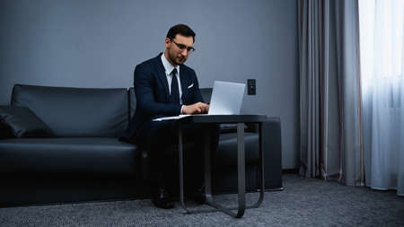 Businessman using laptop in modern hotel roomの写真素材
