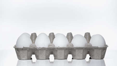 carton container with raw eggs on white