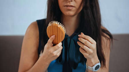 cropped view of upset woman holding hair brushの写真素材