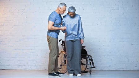 senior man supporting handicapped asian wife near wheelchairの写真素材