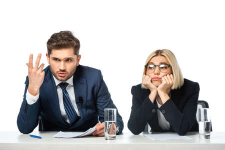 discouraged broadcaster gesturing near upset colleague at workplace isolated on whiteの写真素材