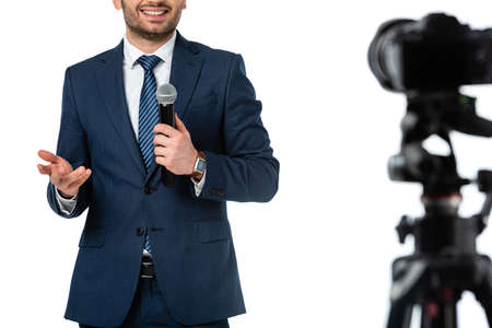 cropped view of smiling news anchor with microphone near digital camera isolated on white, blurred foregroundの写真素材