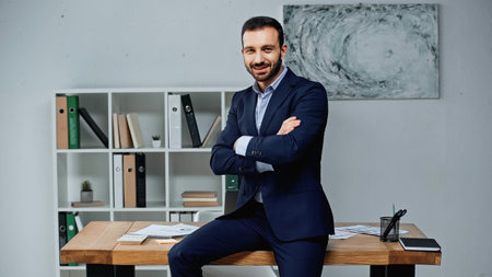 Smiling businessman sitting with crossed arms on working table