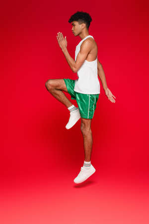 full length of sportive african american man in green shorts working out on redの写真素材