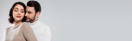 Man standing near pretty brunette woman isolated on gray, banner