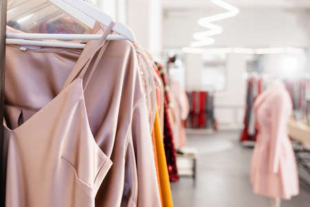 Stylish clothes on hangers in showroom on blurred background