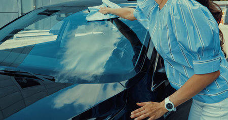 cropped view of woman holding rag while wiping car windshieldの写真素材