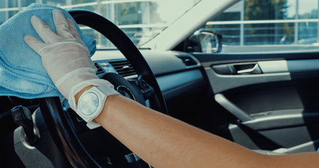 cropped view of woman in latex glove wiping steering wheel with ragの写真素材