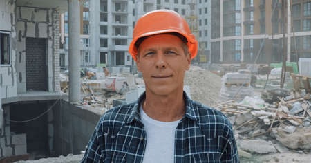 builder in hard hat smiling at camera on construction siteの写真素材