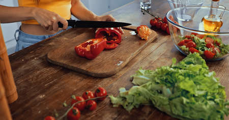 cropped view of woman cutting red bell pepper near ingredientsの写真素材