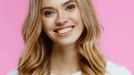 happy young woman smiling while looking at camera isolated on pinkの写真素材