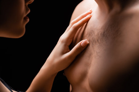 Cropped view of woman touching chest of boyfriend isolated on blackの写真素材