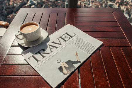 cup of coffee and travel newspaper on wooden table in cafeの写真素材