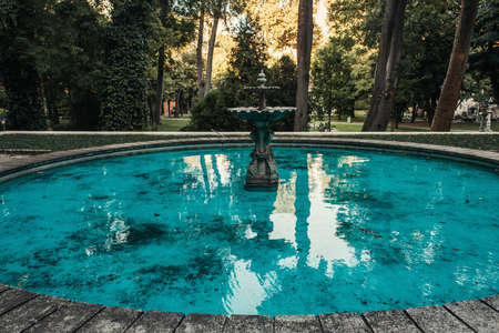 decorated fountain and artificial pond with blue water in park