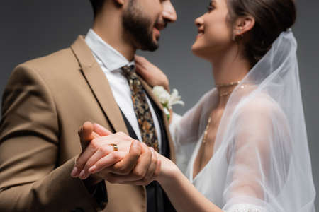 Wedding ring on finger of smiling bride dancing with arabian groom on blurred background isolated on grayの写真素材