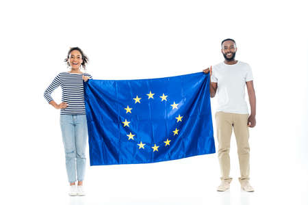 young african american couple smiling at camera while holding european union flag on whiteの写真素材
