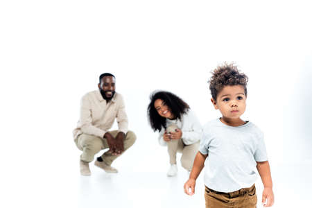 little african american boy standing near cheerful parents on blurred background on whiteの写真素材