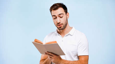 man in white t-shirt reading book isolated on blue
