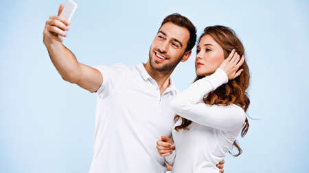 young couple taking selfie isolated on blue