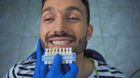 overhead view of smiling man near dentist holding teeth color paletteの写真素材