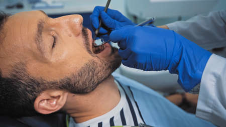 dentist examining teeth of man with mouth mirror and dental probeの写真素材