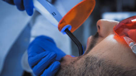 cropped view of dentist holding ultraviolet lamp near patientの写真素材