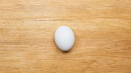 top view of white chicken egg on wooden table