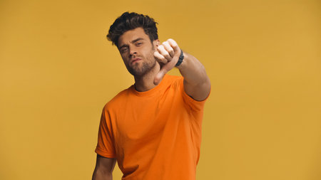 displeased man showing thumb down isolated on yellow