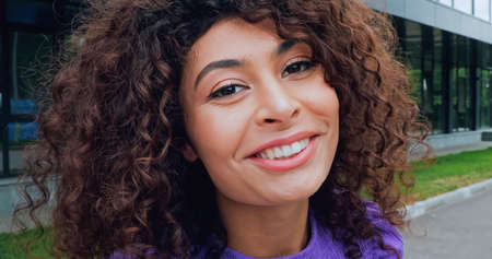 close up of pleased young woman looking at camera and smiling outsideの写真素材