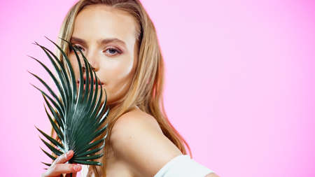 Portrait of young woman with palm leaf on pinkの写真素材