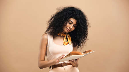 Young hispanic woman reading book isolated on beigeの写真素材