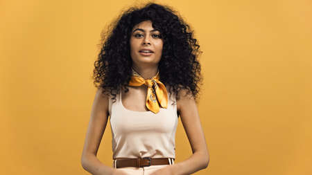 Smiling young hispanic woman looking at camera isolated on yellowの写真素材