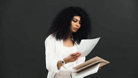 hispanic woman holding paper folder and documents isolated on blackの写真素材