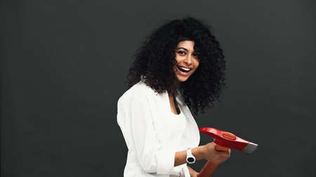 Smiling hispanic woman holding ax isolated on blackの写真素材