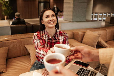 blurred man giving cup of tea to happy womanの写真素材
