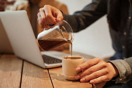 cropped view of man pouring coffee from glass jug into cupの写真素材