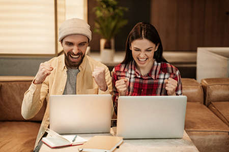 excited freelancers using laptops and smiling in cafeの写真素材