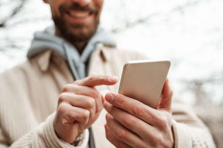 cropped view of bearded man pointing with finger at smartphoneの写真素材