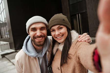 cheerful couple in beanie hats smiling at cameraの写真素材