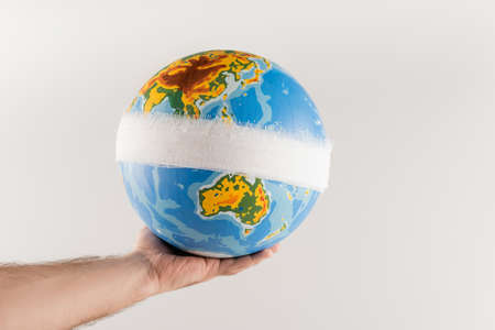 partial view of man holding bandaged globe isolated on gray, ecology conceptの写真素材