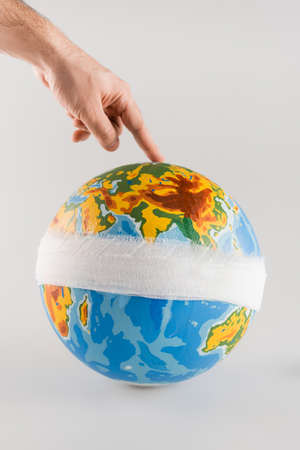 cropped view of man touching bandaged globe on gray, ecology concept