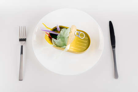 top view of tin with plastic rubbish on plate near fork and knife on white, ecology conceptの写真素材