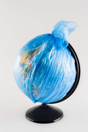 globe packed in plastic bag isolated on gray, ecology concept