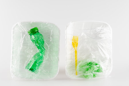 top view of plastic plates with bottle and fork packed in polyethylene, ecology conceptの写真素材