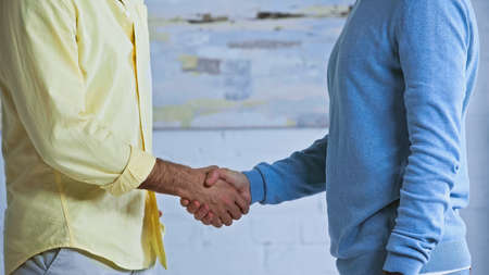cropped view of businessmen shaking hands in officeの写真素材