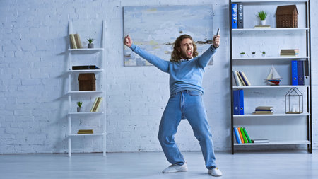 full length view of excited businessman showing win gesture and screaming in officeの写真素材