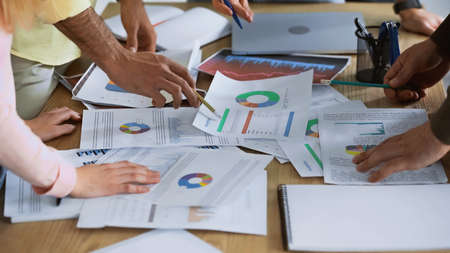 cropped view of businessman pointing with pencil at document near partners on blurred foregroundの写真素材